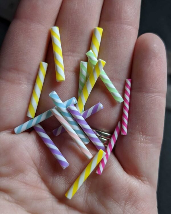 A hand holding some colorful straws in their palm