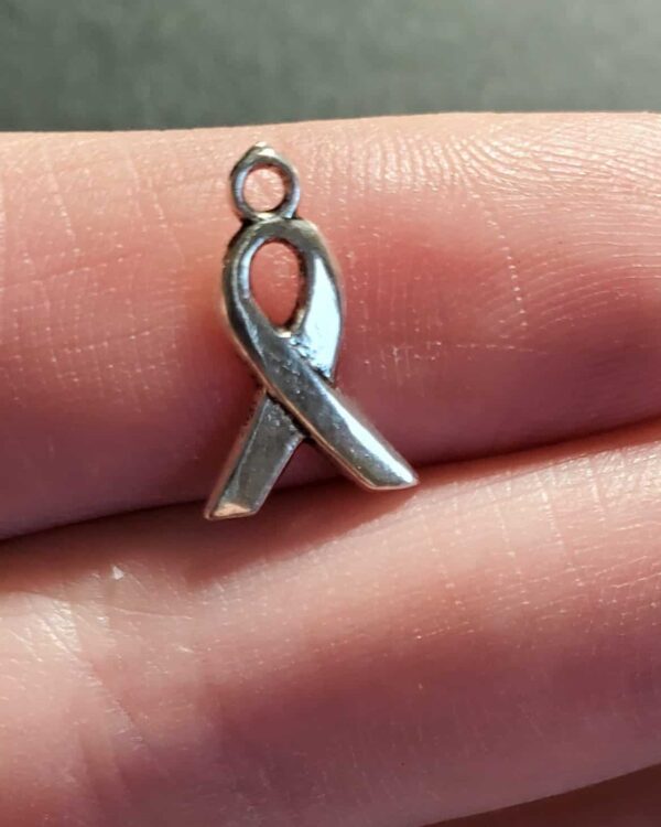 A person holding onto a silver ribbon charm