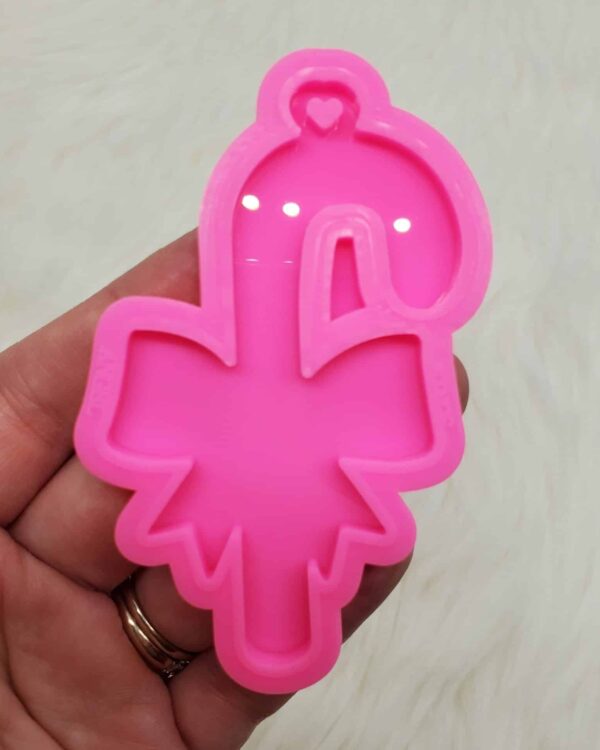 A pink flamingo shaped cookie cutter in someone 's hand.