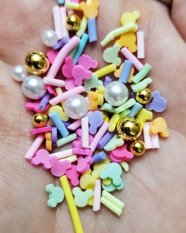 A hand holding some candy with gold and pearls