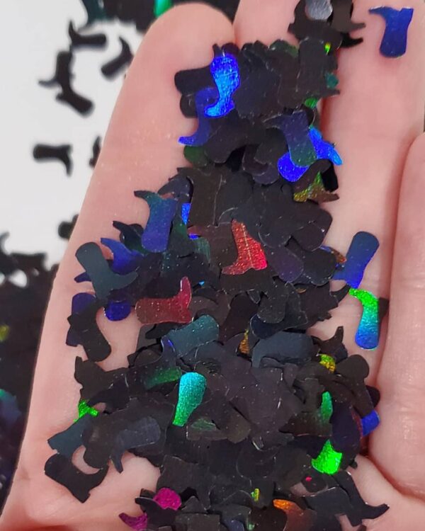 A hand holding pieces of black paper with blue, green and red shapes.