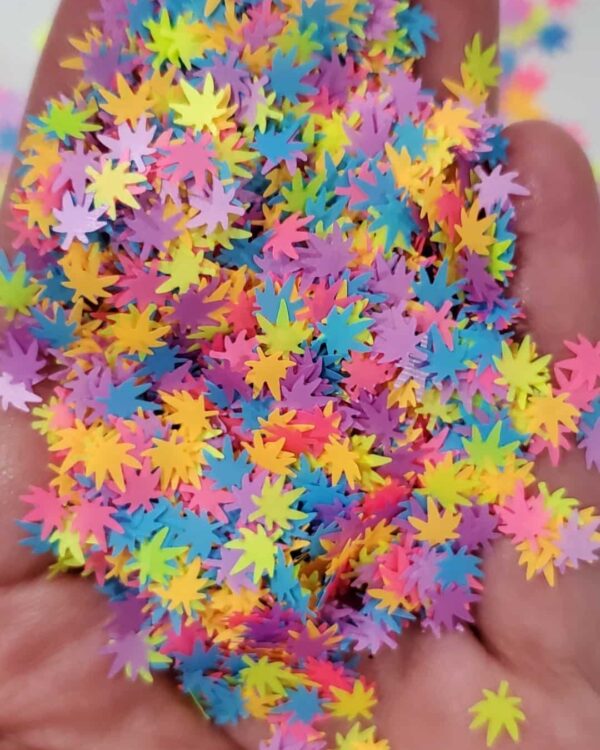 A hand holding colorful confetti in the shape of stars.