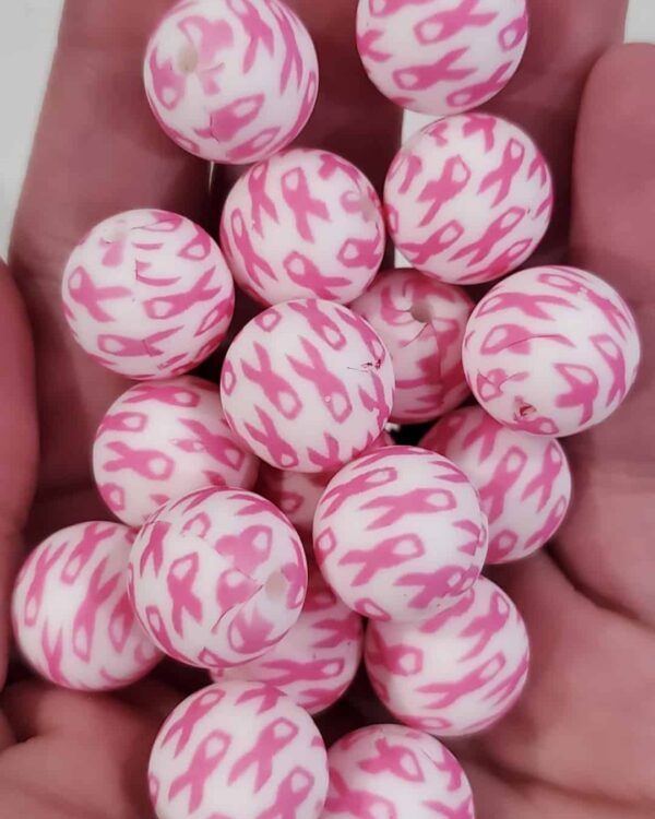 A hand holding pink and white balls with breast cancer awareness.