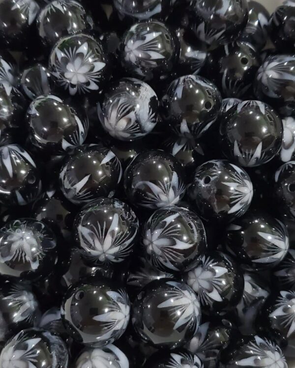 A pile of black and white beads with marijuana leaf designs.