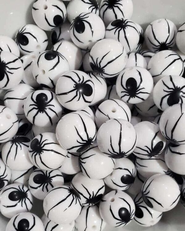 A pile of white and black beads with spider designs.